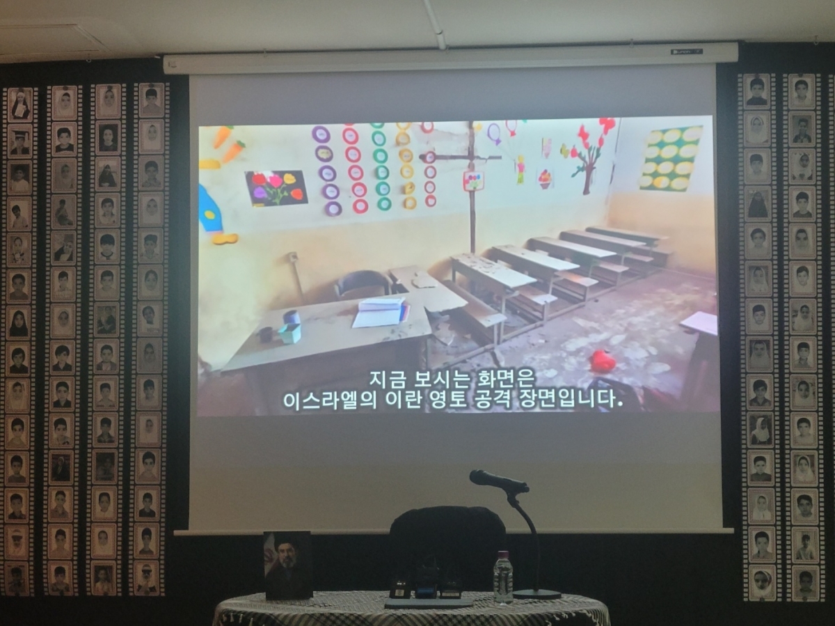 주한이란대사관에서 ‘피로 물든 천사들’ 다큐멘터리가 상영되고 있다. 화면 양 옆으로는 초등학교 폭격으로 희생된 학생들의 사진이 부착돼 있다. 이주원 기자