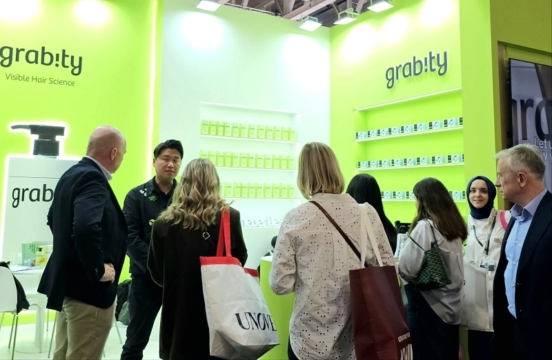 그래비티샴푸 전시 부스를 찾아 제품 설명을 듣는 관람객들