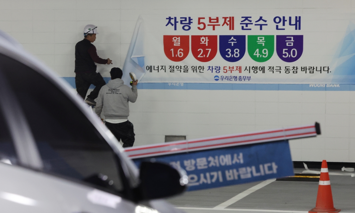 서울 중구 우리은행 본점 주차장에서 관계자들이 ‘차량 5부제’ 관련 안내문을 붙이고 있다. 중동 전쟁으로 에너지 수급 불안이 커진 가운데 금융지주들도 정부의 에너지 절감 정책에 동참하고 나섰다. 연합뉴스