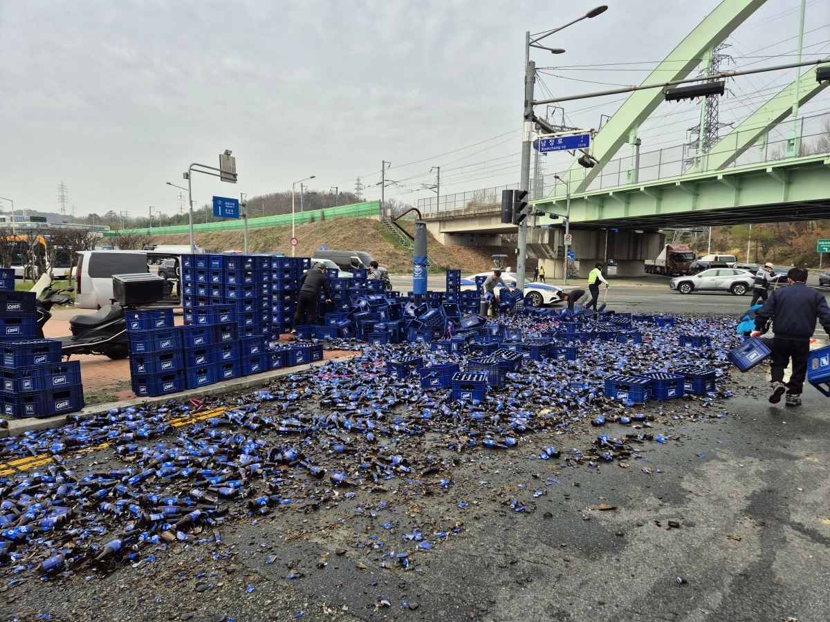 30일 오전 울산 남구 두왕사거리 인근 도로를 달리던 트럭에서 맥주병이 쏟아져 경찰이 수습하고 있다. 울산경찰청 제공
