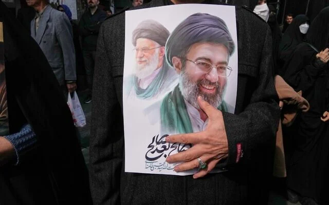지난 11일 이란 테헤란에서 열린 장례식에서 한 조문객이 최고 지도자 아야톨라 알리 하메네이(왼쪽)의 후계자인 아야톨라 모즈타바 하메네이(오른쪽)의 초상화가 그려진 포스터를 들고 있다. 테헤란 AP 연합뉴스
