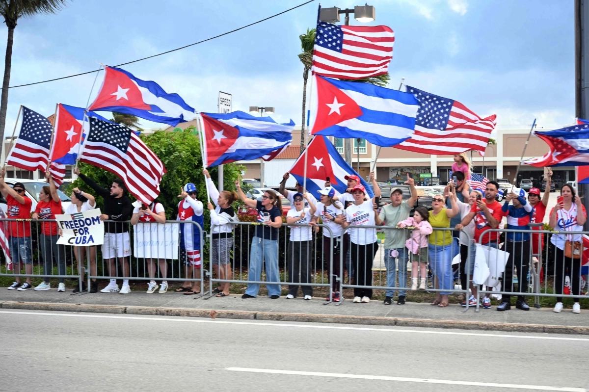 29일(현지시간) 미국 플로리다주 팜비치 국제공항 인근에서 도널드 트럼프 대통령의 차량 행렬이 지나가자 시민들이 쿠바와 미국 국기를 흔들고 있다. AFP 연합뉴스