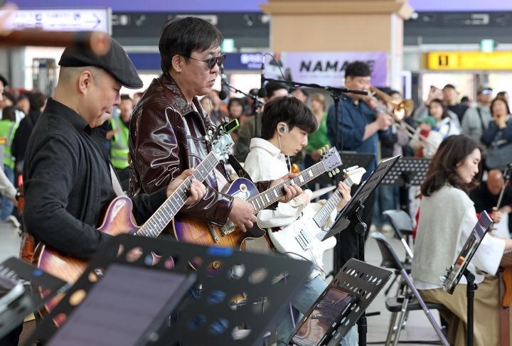 최휘영(왼쪽 두 번째) 문화체육관광부 장관이 1일 ‘문화가 있는 날’의 매주 수요일 확대 시행을 기념해 서울역에서 열린 ‘수요일은 문화요일, 문화로 놀자!’ 공연에서 기타 연주를 하고 있다.  문화체육관광부 제공