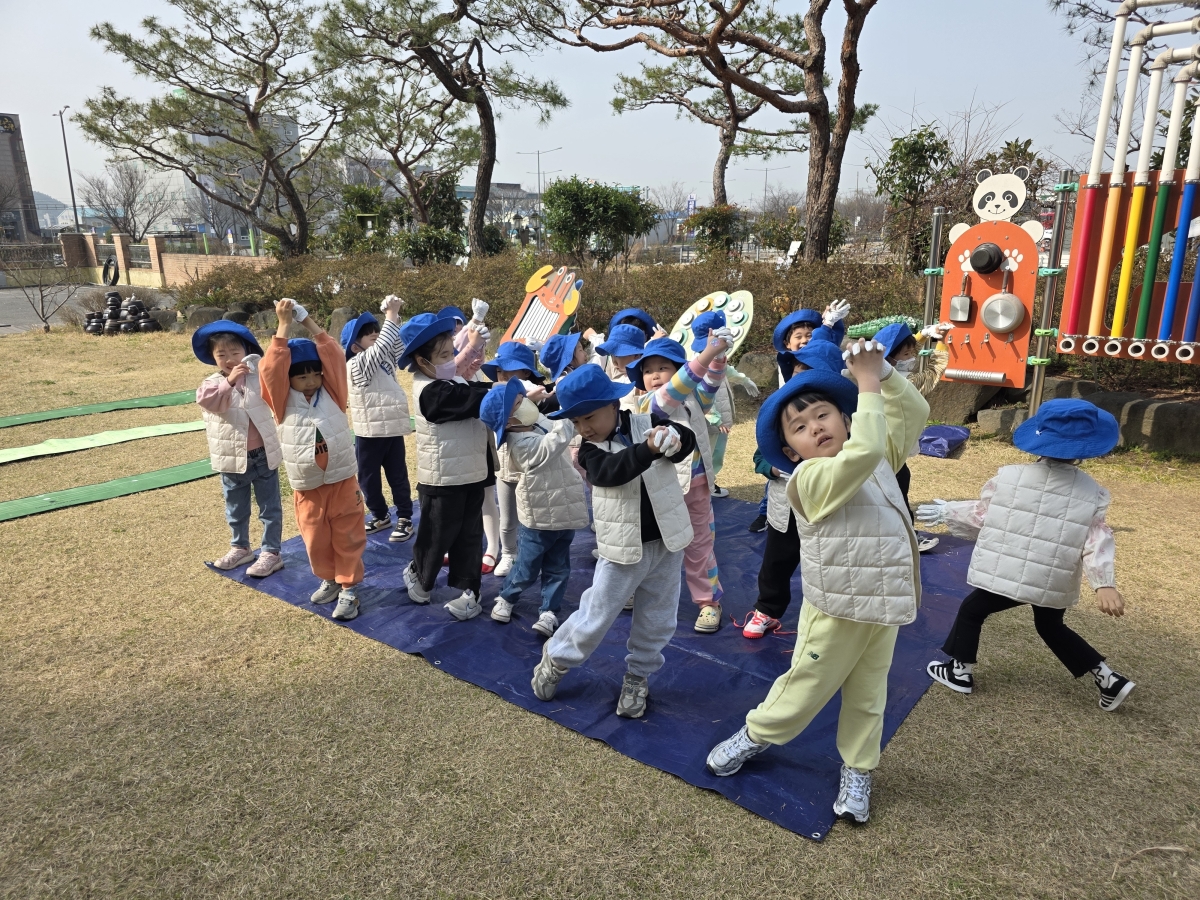 광주 해달유치원 천연 잔디 운동장에서 어린이들이 파크골프 수업에 참여하고 있다. 넓은 녹지 공간 속에서 놀이와 교육이 결합된 활동이 펼쳐지고 있다.