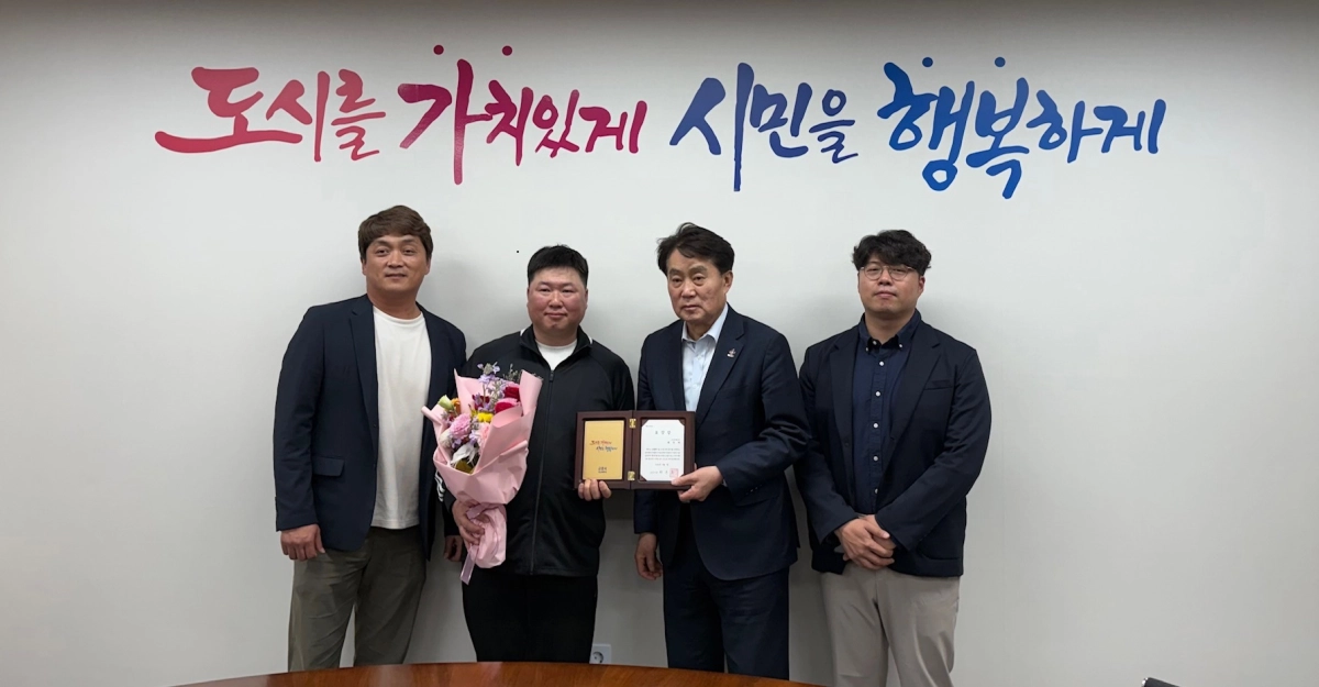 하은호 군포시장(오른쪽 두 번째)이 생활폐기물 수거 과정에서 발견한 거액의 현금과 귀중품을 주인에게 돌려준 환경미화원 배영제(왼쪽 두 번째) 씨에게 ‘청소분야 지역사회 청렴실천 유공’ 표창을 수여하고 기념 촬영을 하고 있다. (군포시 제공)