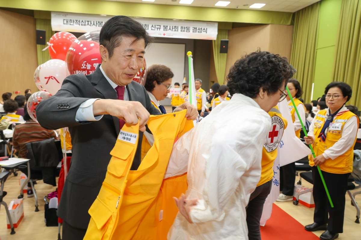 전성수(왼쪽) 서초구청장이 지난 1일 서초구청 대강당에서 열린 ‘서초구 동 적십자봉사회 합동 결성식’에서 봉사단원에게 조끼를 입혀주고 있다. 서초구 제공
