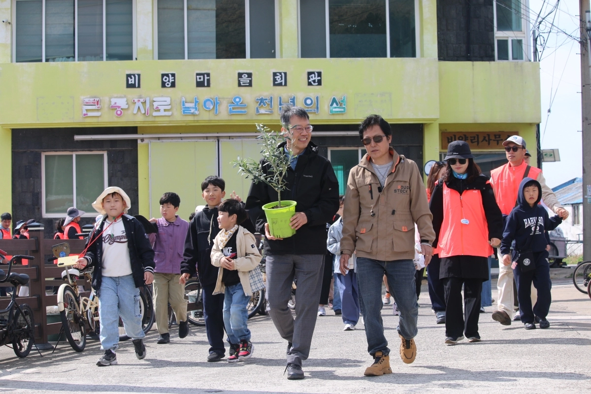 드론 배송된 올리브 묘목을 운반하는 이영근 한국관광공사 제주지사장(앞줄 왼쪽)과 고성민 비양리 이장(오른쪽). 한국관광공사 제공.