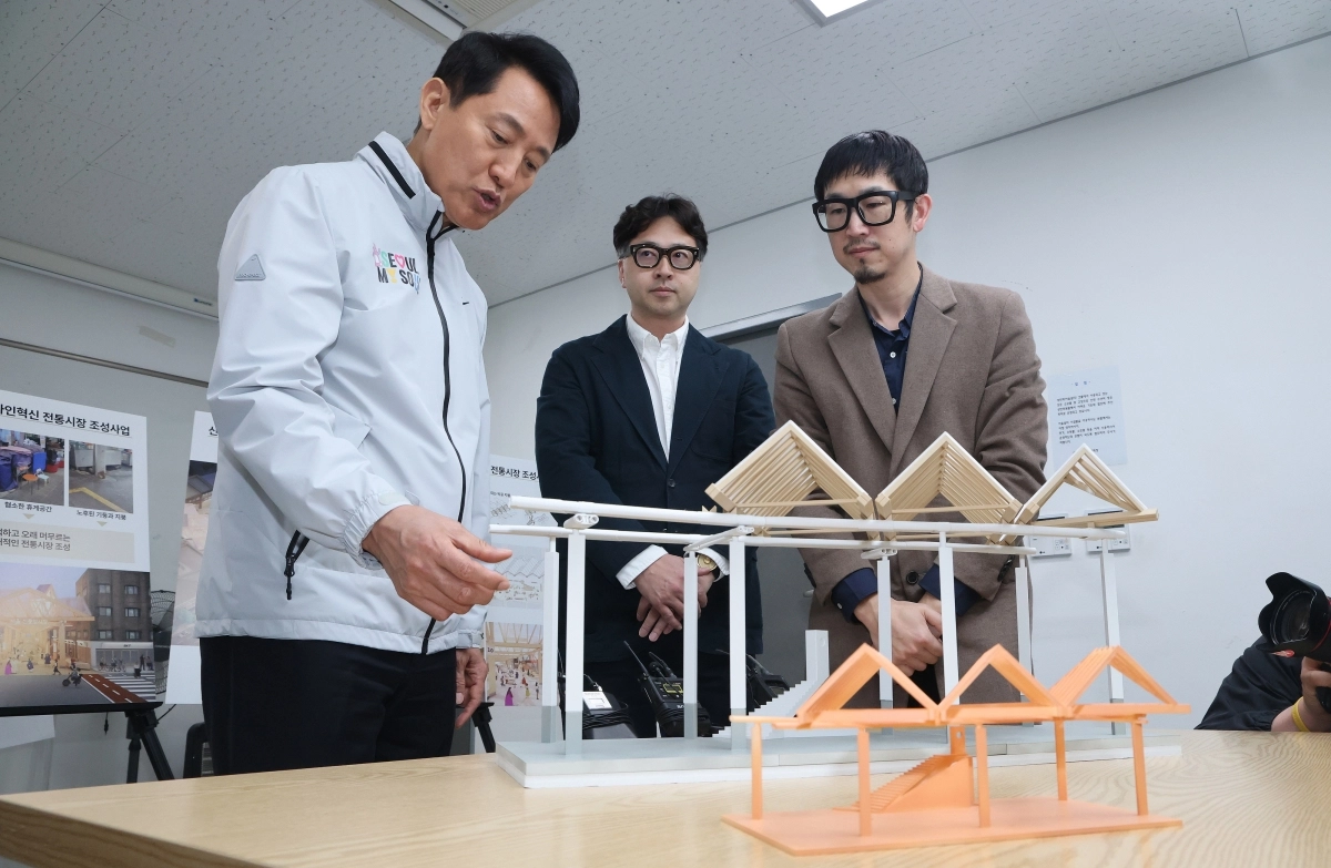 오세훈(왼쪽) 서울시장이 8일 중구 황학동 신중앙시장에서 ‘디자인 혁신 전통시장 사업’에 따라 탈바꿈할 시장의 설계 모형을 가리키며 관계자들과 대화하고 있다. 서울시 제공