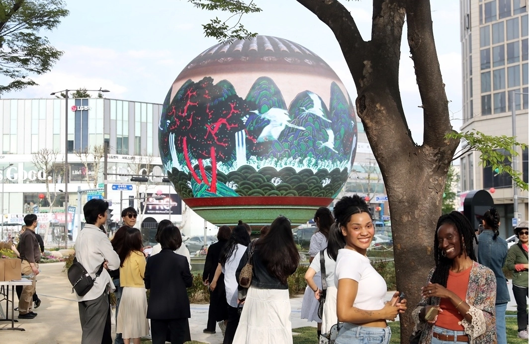 송파구 석촌호수 서호에 설치된 구형 미디어아트 조형물 ‘더 스피어’에 외국인 관광객들이 모여 팸투어를 진행하고 있다. 송파구 제공