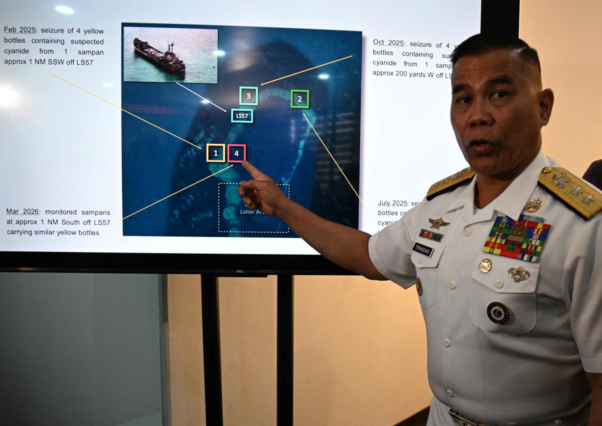 필리핀 해군 대변인이 2026년 4월 13일 마닐라에서 열린 기자회견에서 남중국해 분쟁 해역인 세컨드 토머스 암초에서 중국 어부들로부터 시안화물이 들어있다고 의심되는 노란색 병을 압수한 사진을 가리키고 있다. 마닐라 AFP 연합뉴스
