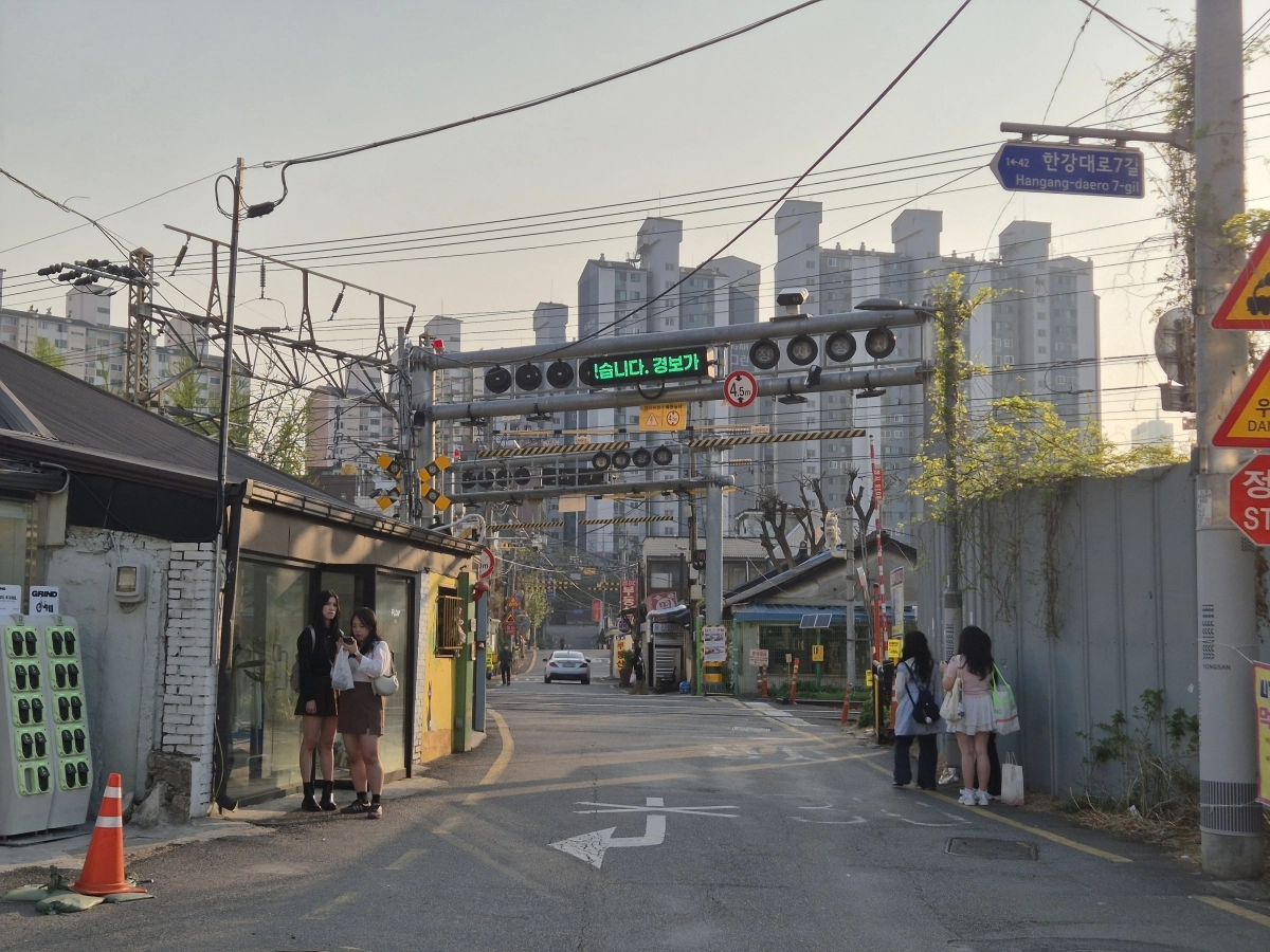 여행객들이 지난 14일 서울 용산구 한강로3가 백빈건널목에서 사진을 찍고 있다. 오른편 철제 가림막 너머는 용산국제업무지구 개발사업 대상지다.