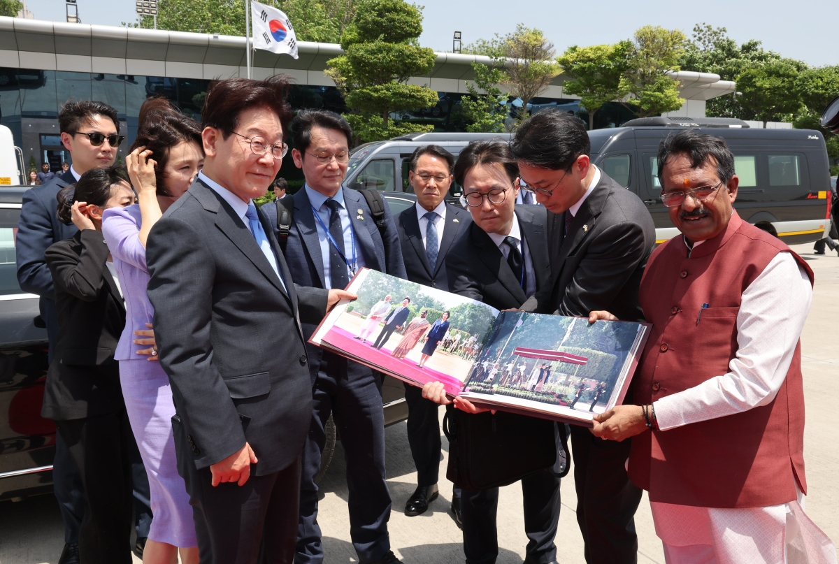 인도 국빈 방문을 마친 이재명 대통령과 김혜경 여사가 21일(현지시간) 뉴델리 팔람 군비행장에서 베트남행 공군 1호기 탑승 전 사진첩을 선물 받고 있다. 뉴델리 뉴스1