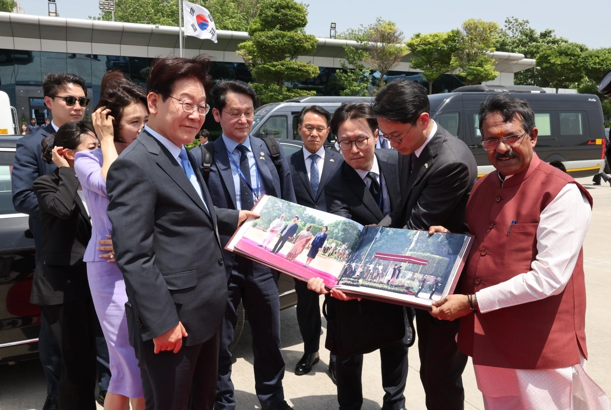 인도 국빈 방문을 마친 이재명 대통령과 김혜경 여사가 21일(현지시간) 뉴델리 팔람 군비행장에서 베트남행 공군 1호기 탑승 전 사진첩을 선물 받고 있다. 뉴델리 뉴스1