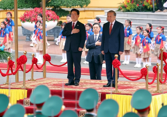 베트남을 국빈 방문한 이재명 대통령이 22일(현지시간) 하노이 주석궁에서 열린 공식환영식에서 국기에 경례하고 있다. 오른쪽은 또 럼 공산당 서기장 겸 국가주석 2026.4.22 <br>연합뉴스