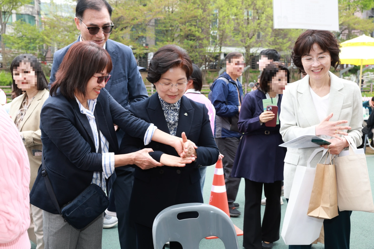 김미경(가운데) 은평구청장이 지난 17일 은평구 불광천 수변무대 일대에서 열린 장애인의 날 기념식 이후 한 청각장애인에게 수어를 배우고 있다.  은평구 제공