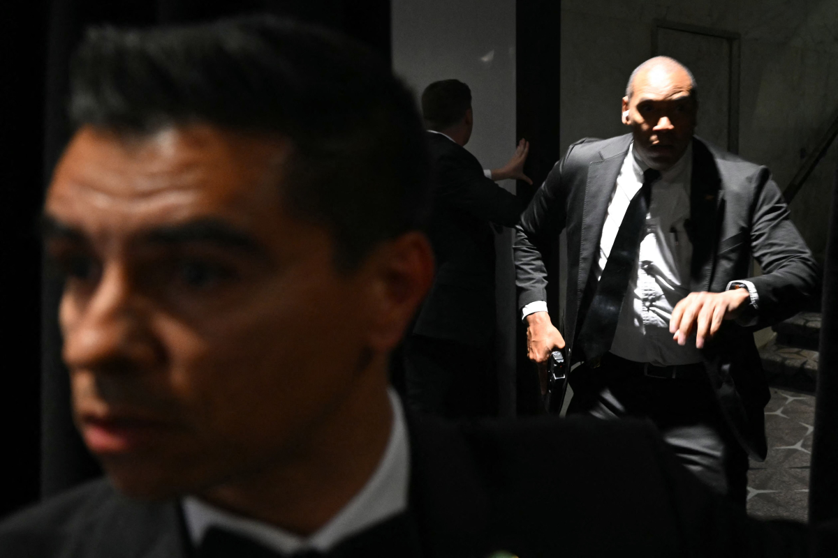 25일(현지시간) 미국 워싱턴 DC 워싱턴 힐튼 호텔에서 열린 백악관 기자단 만찬 도중 큰 폭발음이 들리자 경호원들이 권총을 뽑고 있다. 워싱턴DC AFP 연합뉴스