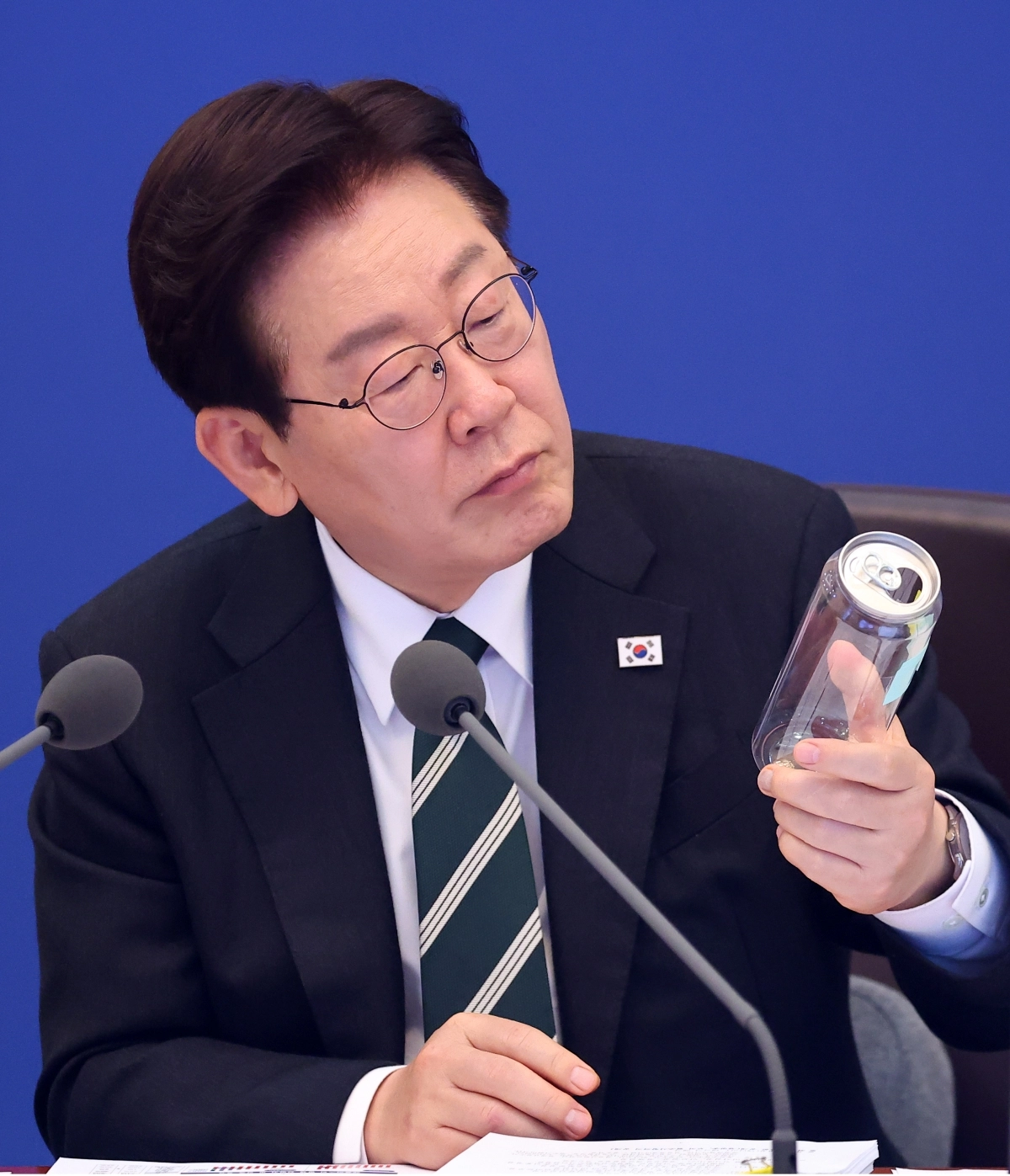 이재명 대통령이 28일 청와대에서 열린 국무회의에서 김성환 기후에너지환경부 장관의 발언을 들으며 투명 PET와 알루미늄 뚜껑으로 이뤄진 캔시머 용기를 살펴보고 있다. 정부는 2030년까지 나프타로 만든 플라스틱 폐기량을 예상보다 30% 이상 줄인다는 목표를 확정했다. 뉴스1