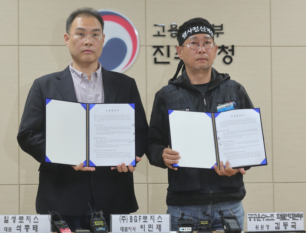 이민재(왼쪽) BGF로지스 대표와 김동국 민주노총 화물연대 위원장이 30일 고용노동부 진주지청에서 서명한 단체합의서를 들어 보이고 있다. 연합뉴스