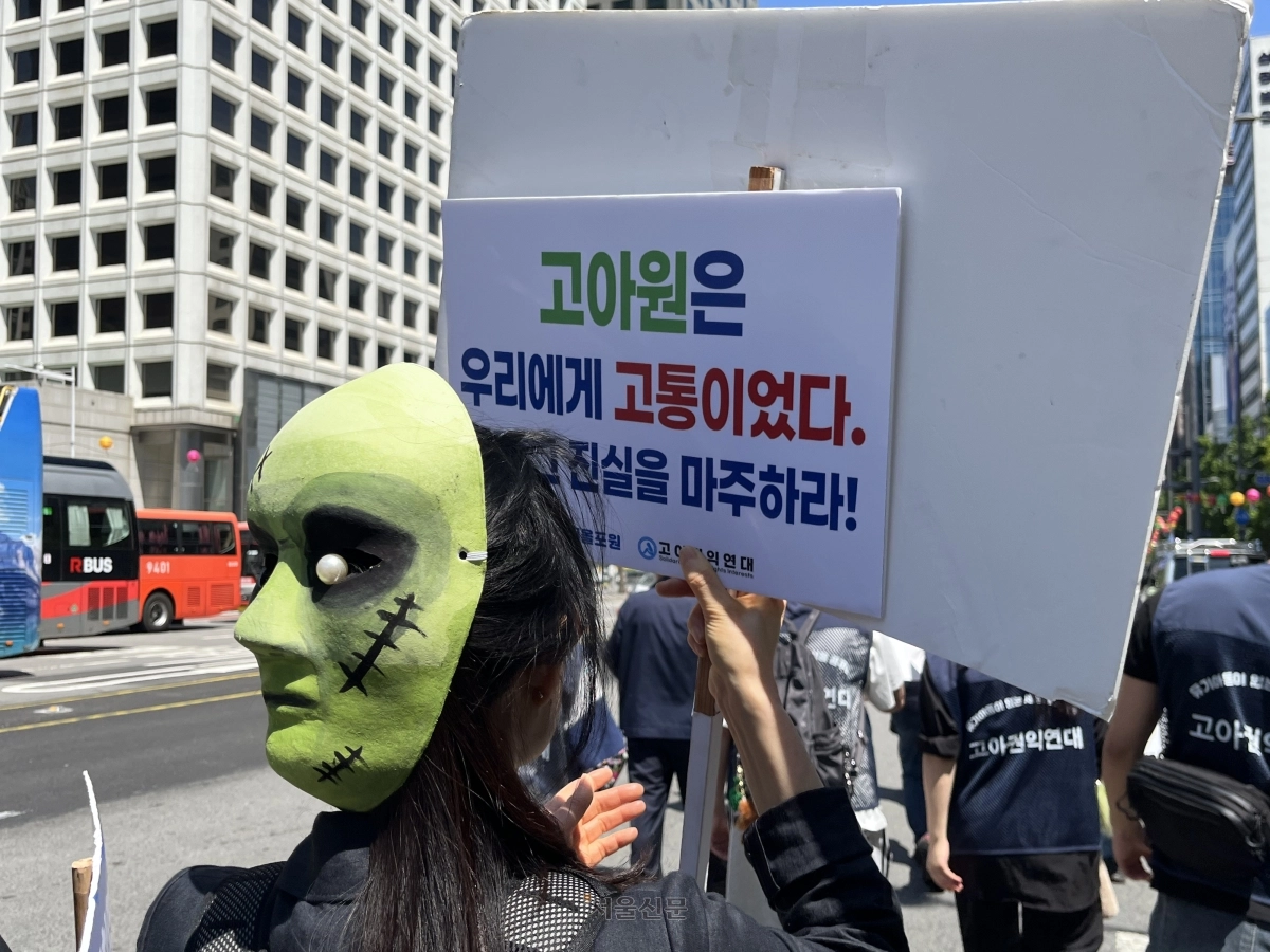 어린이날인 5일 서울 중구 서울역 앞에서 열린 ‘고아 프랑켄슈타인 가두행진’에서 가면을쓴 참가자가 피켓을 들고 있다. 박다운 수습기자