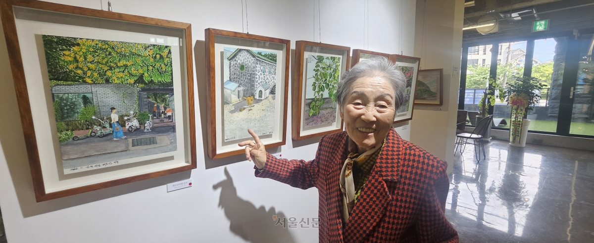 좌기춘 할머니가 지난 4일 제주시 도남동 델문도뮤지엄에서 열리고 있는 자신의 첫 개인전에서 그림 ‘우리집 바두기’를 설명하며 웃고 있다.