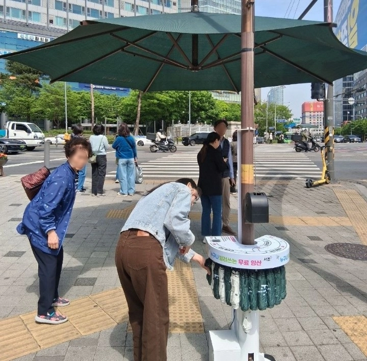 서울 서초구 횡단보도 앞에 설치된 ‘서리풀양산 스마트 대여 시스템’에서 주민들이 양산을 대여하고 있다. 서초구 제공