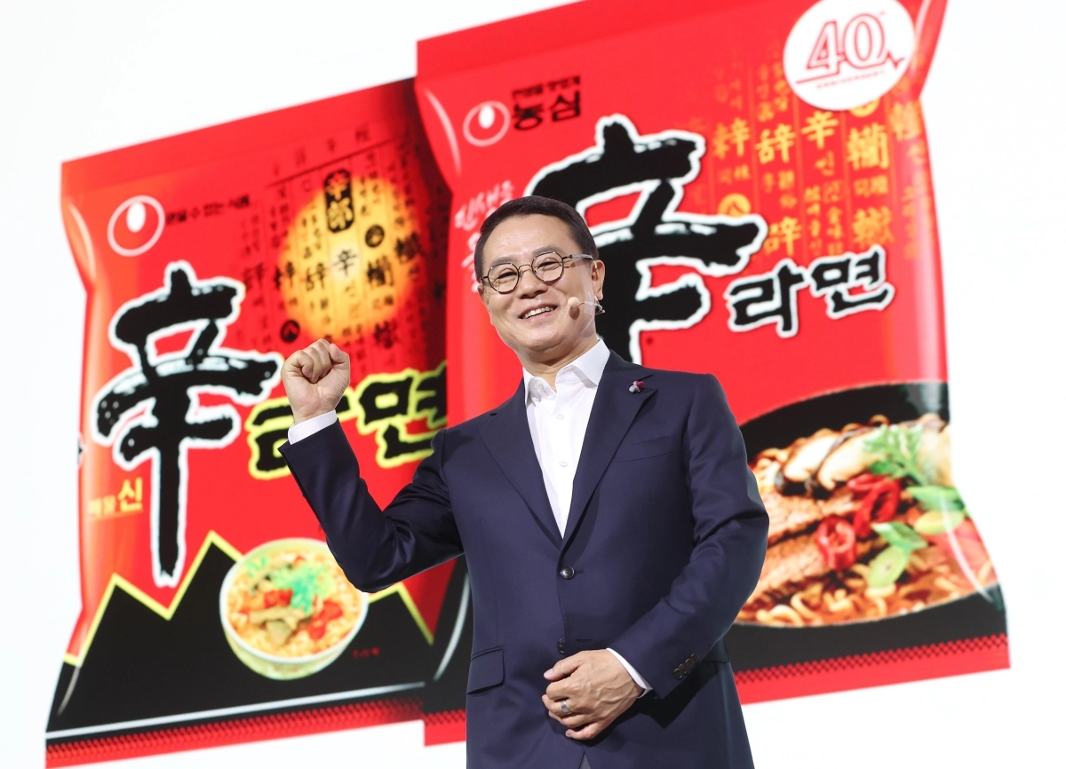 조용철 농심 대표가 13일 서울 중구 롯데호텔에서 열린 신라면 출시 40주년 기자간담회에서 라면 봉지 사진을 배경으로 취재진을 향해 포즈를 취하고 있다. 뉴스1