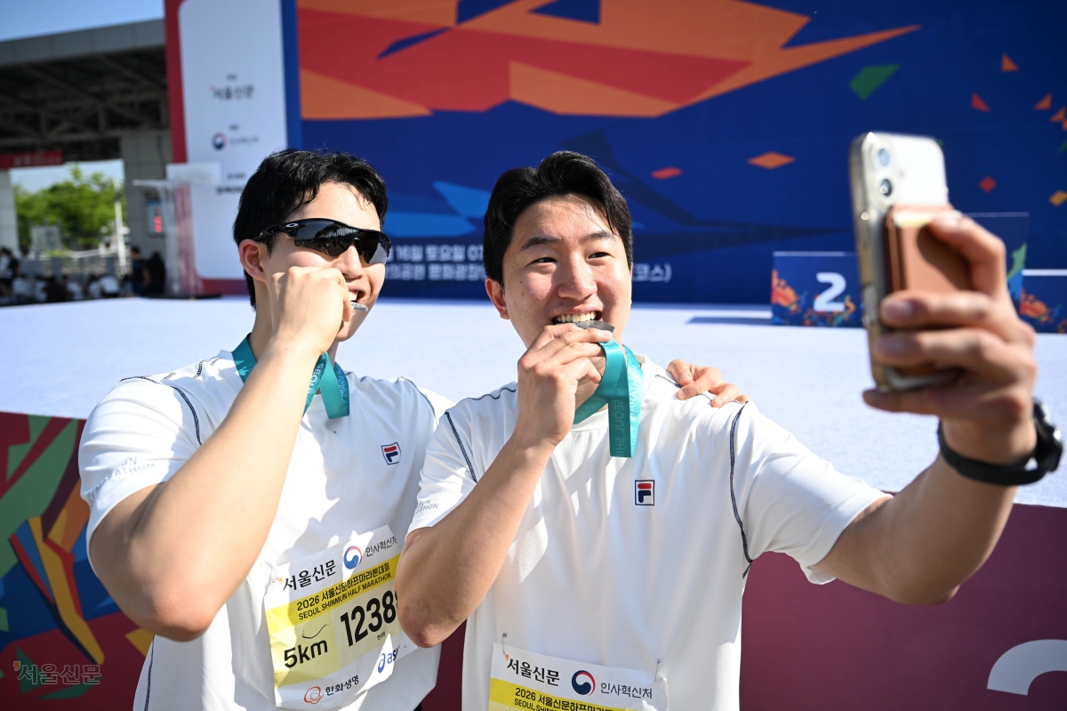 참가자들이 기념 메달을 깨물며 완주의 기쁨을 사진으로 남기고 있다. 이지훈 기자