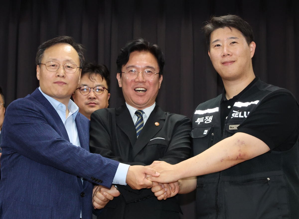 20일 경기도 수원시 장안구 경기고용노동청에서 열린 삼성전자 임금협상을 마친 후 여명구 삼성전자 DS(디바이스솔루션·반도체 사업 담당) 피플팀장과 최승호 삼성그룹 초기업노동조합 삼성전자지부 위원장이 잠정 합의안에 서명한 후 김영환 고용노동부 장관과 손을 맞잡고 있다. 2026.5.20. 공동취재