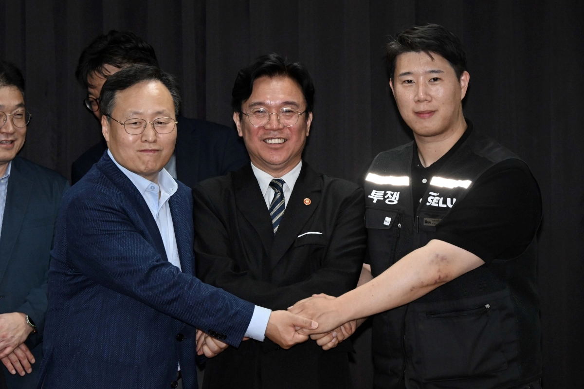 삼성전자 노사 협상이 잠정 합의된 20일 경기도 수원시 장안구 경기지방고용노동청에서 김영훈(가운데) 고용노동부 장관, 최승호(오른쪽) 삼성전자 노조 공동투쟁본부 위원장, 여명구 DS 피플팀장이 손을 맞잡고 있다. 뉴시스