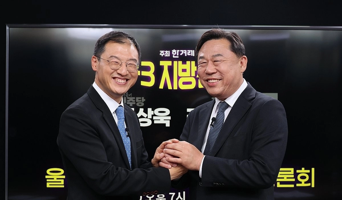 6·3 지방선거 울산시장 후보 단일화에 합의한 더불어민주당 김상욱 후보(왼쪽)와 진보당 김종훈 후보가 지난 20일 서울 마포구 한겨레 신문사에서 열린 단일화 토론회에서 손을 맞잡고 있다. 연합뉴스