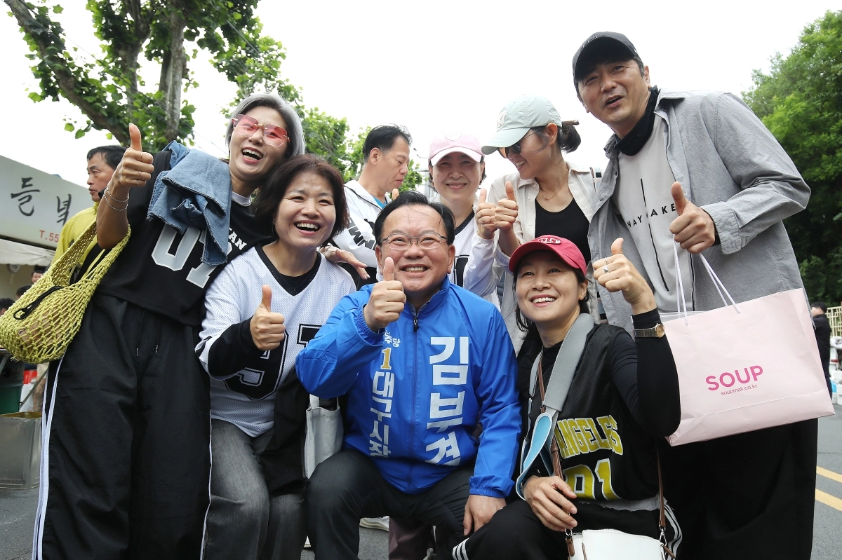 김부겸(가운데) 더불어민주당 대구시장 후보가 지난 23일 대구 중구 달성공원 새벽시장을 찾아 시민들과 함께 엄지척 포즈를 취하며 기념촬영을 하고 있다. 대구 뉴스1