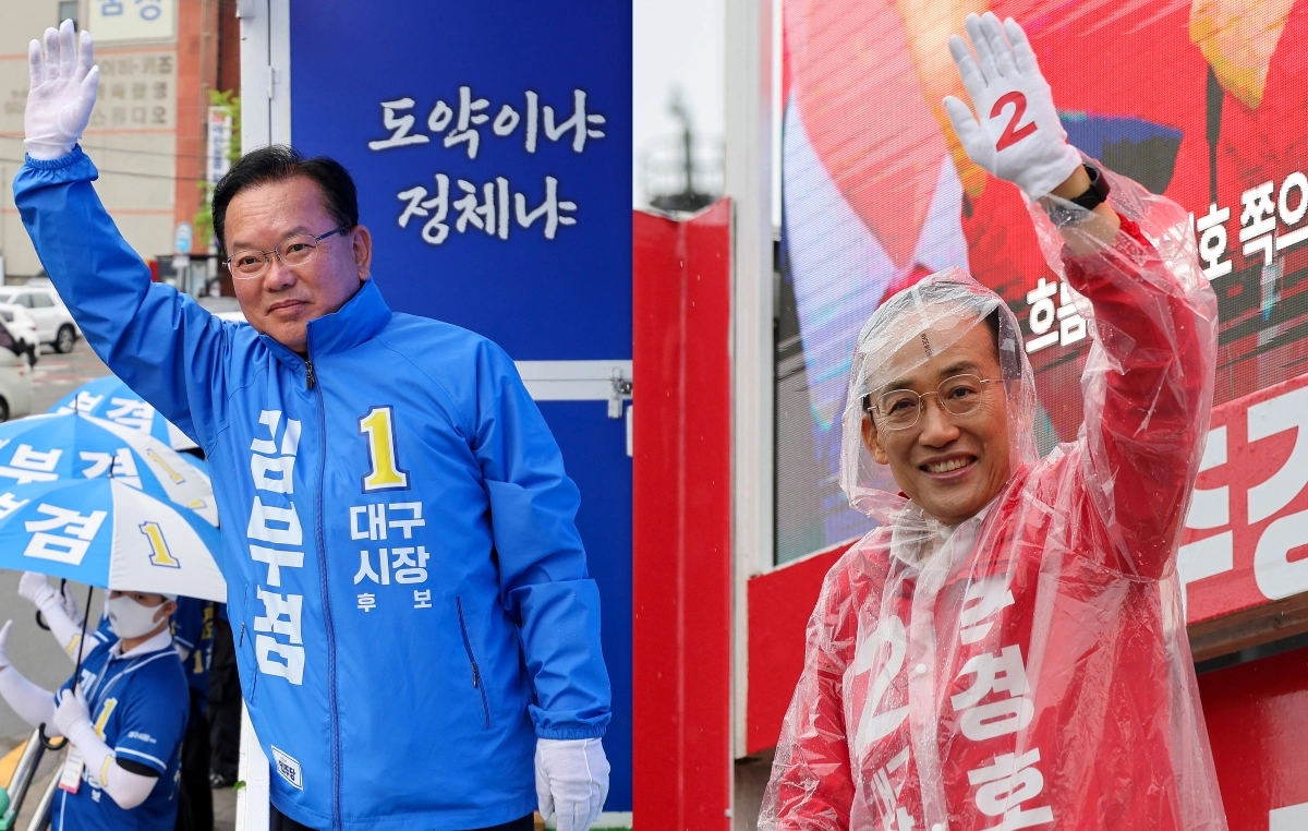6·3 지방선거 대구시장 선거에 출마한 김부겸 더불어민주당 후보가 27일 대구 북구 태전네거리에서 출근길 인사를 하고 있다(왼쪽 사진). 오른쪽 사진은 추경호 국민의힘 후보가 같은 날 북구 팔달교에서 우비를 입고 출근길 인사를 하는 모습. 대구 뉴시스