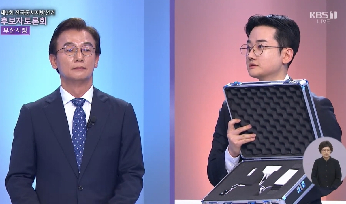 정이한 개혁신당 부산시장 후보가 지난 26일 진행된 부산시선거방송토론위원회 주관 부산시장후보 TV토론회에서 거짓말탐지기를 꺼내보이며 전재수 더불어민주당 후보에게 거짓말 탐지기 조사에 응해 통일교 금품수수 의혹을 떨칠 의향이 있느냐는 취지로 질문하고 있다. KBS 부산 방송화면 캡처