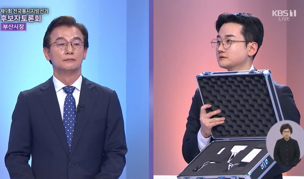 정이한 개혁신당 부산시장 후보가 지난 26일 진행된 부산시선거방송토론위원회 주관 부산시장후보 TV토론회에서 거짓말탐지기를 꺼내보이며 전재수 더불어민주당 후보에게 거짓말 탐지기 조사에 응해 통일교 금품수수 의혹을 떨칠 의향이 있느냐는 취지로 질문하고 있다. KBS 부산 방송화면 캡처