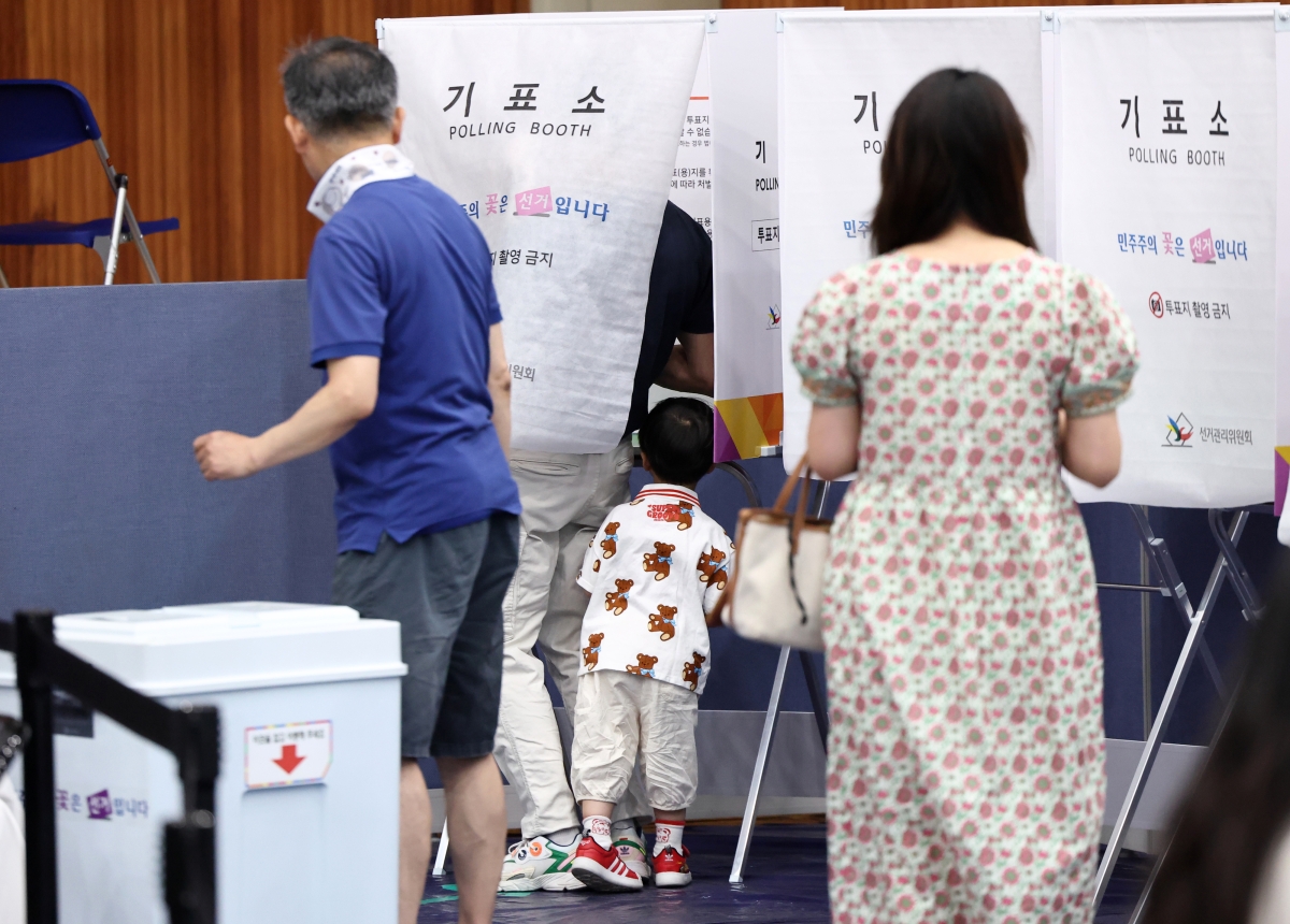 제9회 전국동시지방선거일인 3일 서울 잠전초등학교 체육관에 마련된 잠실본동 제4,5,6투표소에서 한 어린이가 투표하는 아빠를 보고 있다. 2026.6.3 연합뉴스