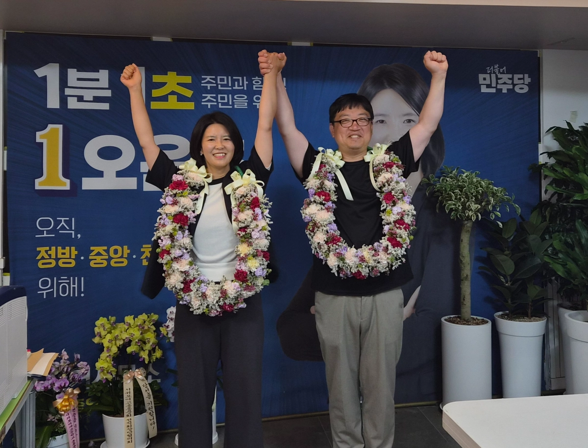 더불어민주당 오은초 제주도의원 후보가 당선돼 남편과 함께 꽃다발을 걸고 만세를 하고 있다. 당선인 선거캠프 제공