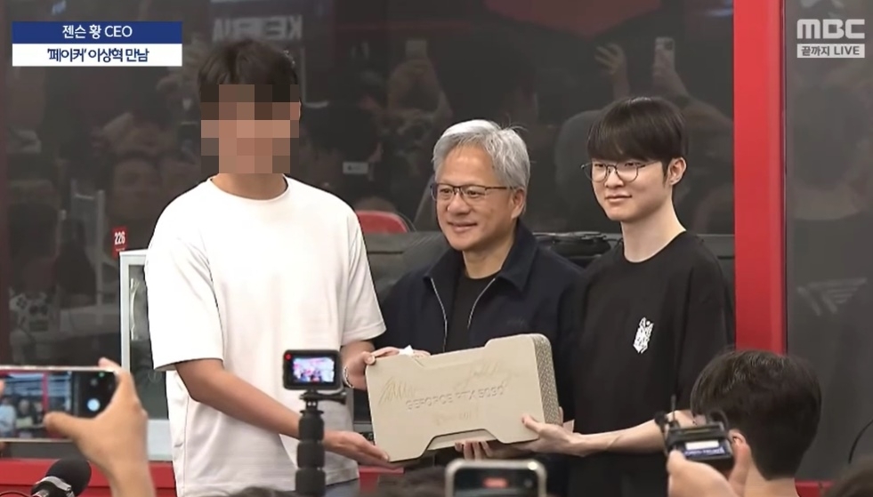 젠슨 황(가운데) 엔비디아 최고경영자(CEO)가 5일 한국을 찾아 방한 첫 일정으로 서울 마포구 티원(T1) 베이스캠프를 찾았다. 황 CEO는 e스포츠 스타 페이커(왼쪽)와 함께 엔비디아의 최신 그래픽 카드 ‘지포스 RTX 5090’에 직접 사인한 뒤 추첨을 통해 현장에 있던 한 시민에게 선물로 증정했다. 자료 : MBC