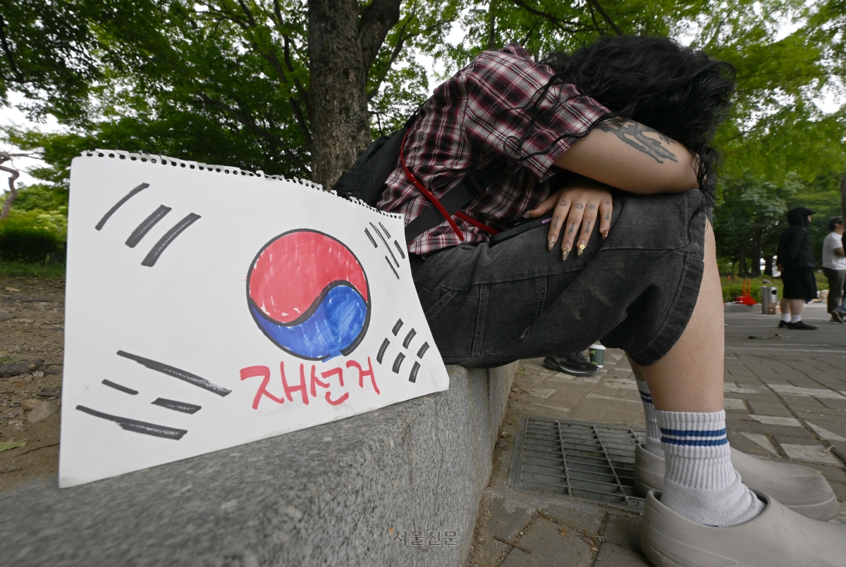 7일 서울 송파구 잠실7동 등 투표소의 개표소인 올림픽공원 핸드볼경기장 앞에서 밤을 새운 한 청년이 쪽잠을 자고 있다. 이지훈 기자