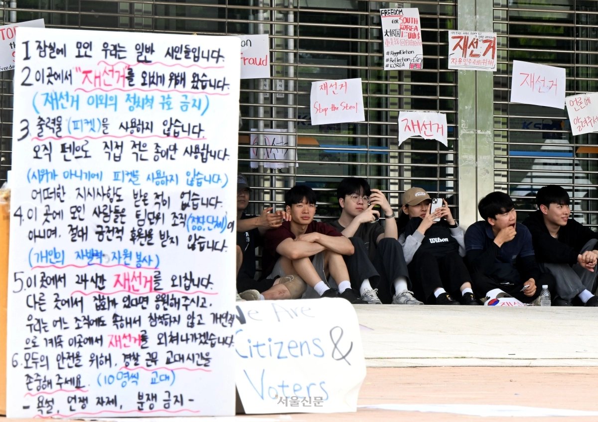 7일 새벽 잠실7동 주민들의 개표소인 서울 송파구 올림픽공원 핸드볼경기장에서 시민들이 경기장 입구에 앉아 있다. 이지훈 기자