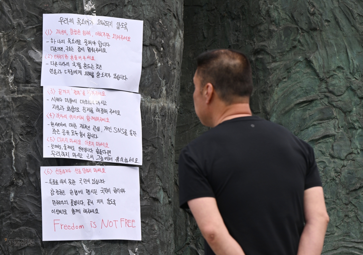 7일 서울 송파구 잠실7동 등 투표소의 개표소인 올림픽공원 핸드볼경기장 앞에서 한 시민이 투표용지 부족 사태를 규탄하는 대자보를 읽고 있다. 이지훈 기자