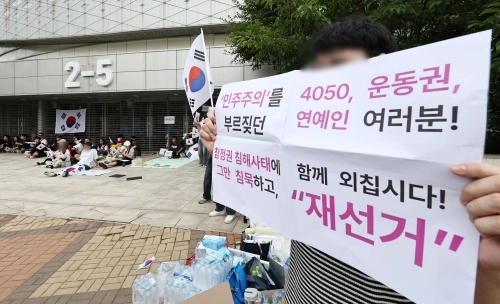6·3 지방선거 투표지 부족 사태를 규탄하며 재선거를 요구하는 ‘잠실 개표소 봉쇄 시위’가 계속되고 있는 7일 서울 송파구 올림픽공원 핸드볼경기장 앞에서 부정선거를 주장하는 한 시민이 손팻말을 들고 있다. 2026.6.7 연합뉴스