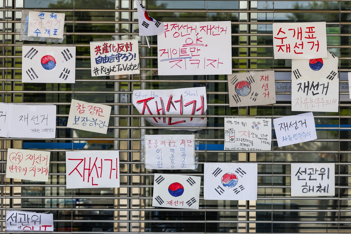 제9회 전국동시지방선거 투표용지 부족 사태에 항의하며 개표소 봉쇄 시위를 이어고 있는 가운데 9일 서울 송파구 올림픽공원 핸드볼경기장에 설치된 개표소 앞에 재선거를 촉구하는 손글씨와 손으로 그린 태극기 등이 붙어 있다. 2026.6.9 뉴시스