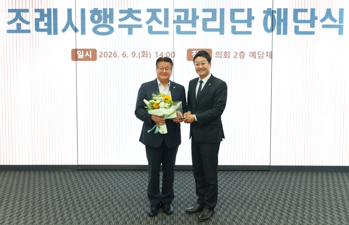 조례시행추진관리단 해단식에서 김진경 경기도의회 의장이 전국 최초로 조례 시행 점검 체계를 안착시킨 안명규 공동단장에게 감사패를 전달한 후 기념촬영을 하고 있다. (사진=경기도의회)