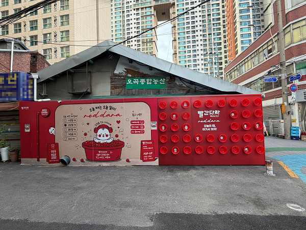 [사진: 동네 쌀가게의 소박한 골조와 ‘빨간다라’의 감각적인 네온 조명 및 레드 오브제가 극적인 대비를 이루는 팝업 전경]