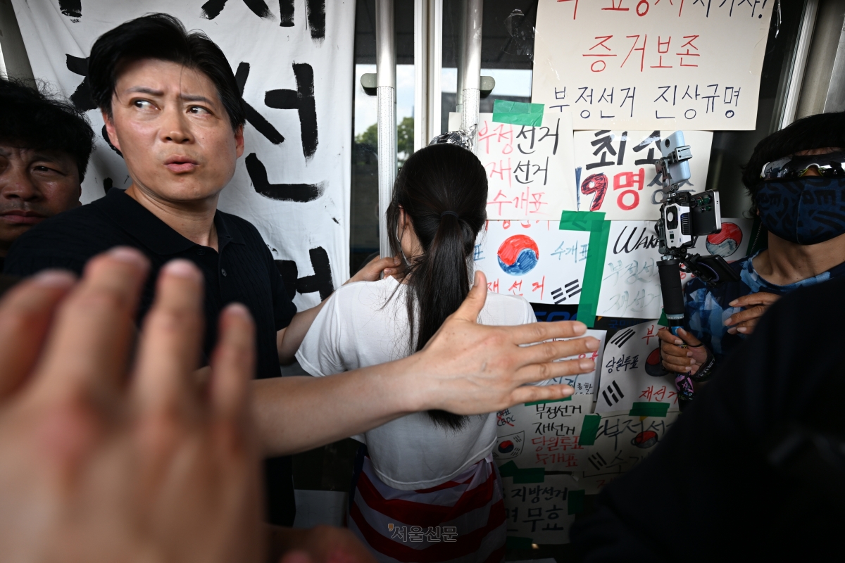 6·3지방선거 투표용지 부족 사태로 촉발된 잠실 개표소 봉쇄 시위가 12일째 이어진 16일 시민들이 서울 송파구 올림픽공원 핸드볼경기장 2-1 출구 앞 문을 지키고 있다. 홍윤기 기자