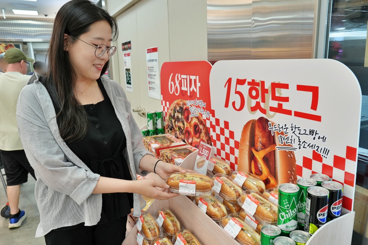 롯데마트 관계자가 지난 15일 서울 송파구 롯데마트 제타플렉스 잠실점에서 매대에 놓인 1500원짜리 핫도그 상품을 소개하고 있다.  롯데마트 제공