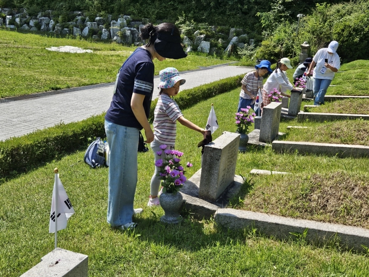 지난 13일 국립4·19민주묘지에서 열린 ‘2026년 강북구 가족봉사단 발대식’에 참여한 한 가족봉사단이 봉사 활동을 하고 있다. 강북구 제공