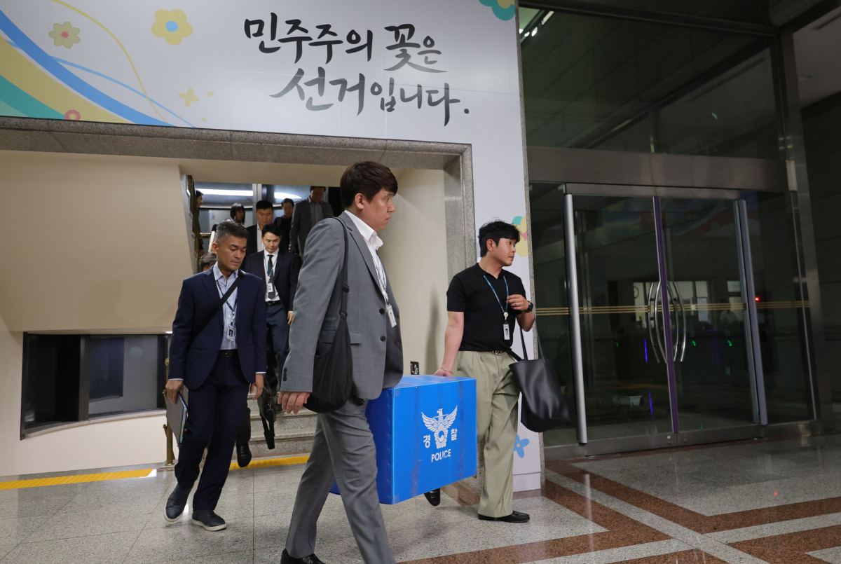 6·3 전국동시지방선거 투표용지 부족 사태를 들여다보고 있는 검경 합동수사본부 관계자들이 11일 경기도 과천 중앙선거관리위원회에서 압수수색을 마친 뒤 압수품을 들고 건물을 나서고 있다. 연합뉴스