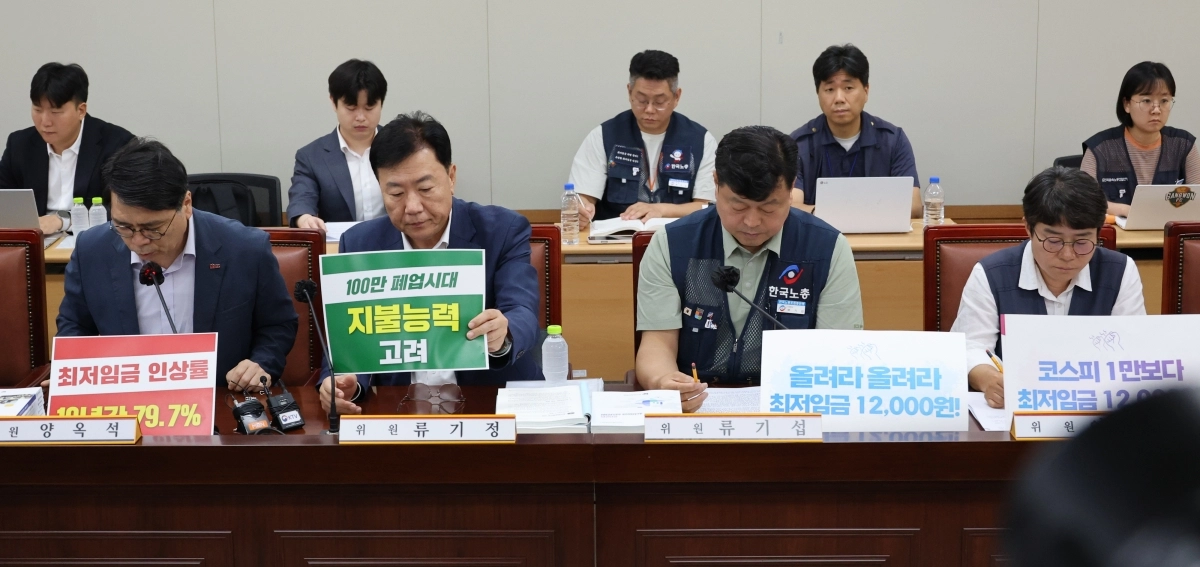23일 정부세종청사 최저임금위원회에서 내년도 최저임금 인상률을 본격 논의하기 위한 제8차 전원회의가 열리고 있다.  사용자위원인 양옥석 중소기업중앙회 인력정책본부장(왼쪽부터)과 류기정 한국경영자총협회(경총) 전무, 근로자위원인 류기섭 한국노총 사무총장과 민주노총 이미선 부위원장이 상반된 피켓을 세워놓고 있다. 연합뉴스