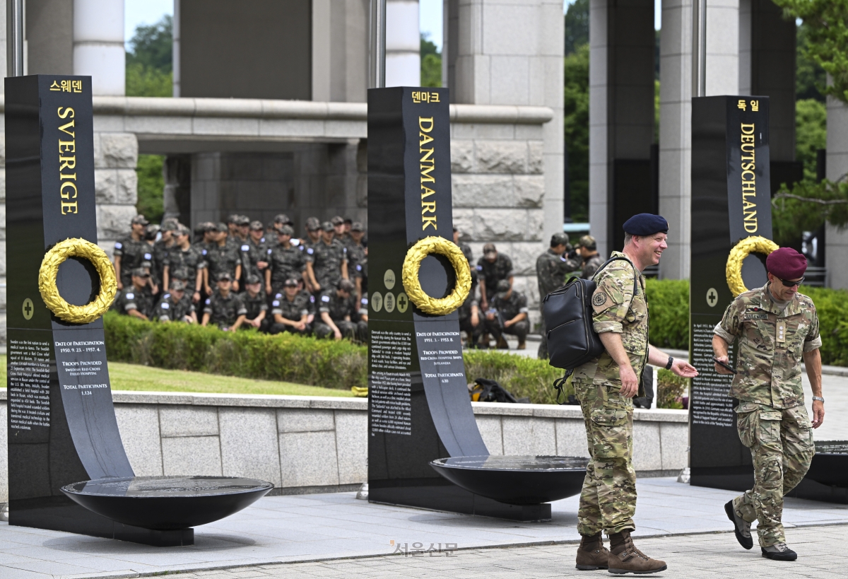 6·25 전쟁 76주년을 하루 앞둔 24일 서울 용산구 전쟁기념관을 찾은 덴마크 군 장병들이 평화의 광장에 마련된 유엔 참전용사 추모비 앞을 지나고 있다. 추모비 너머로 단체 관람을 온 국군 장병들이 보인다. 2026.6.24 이지훈 기자